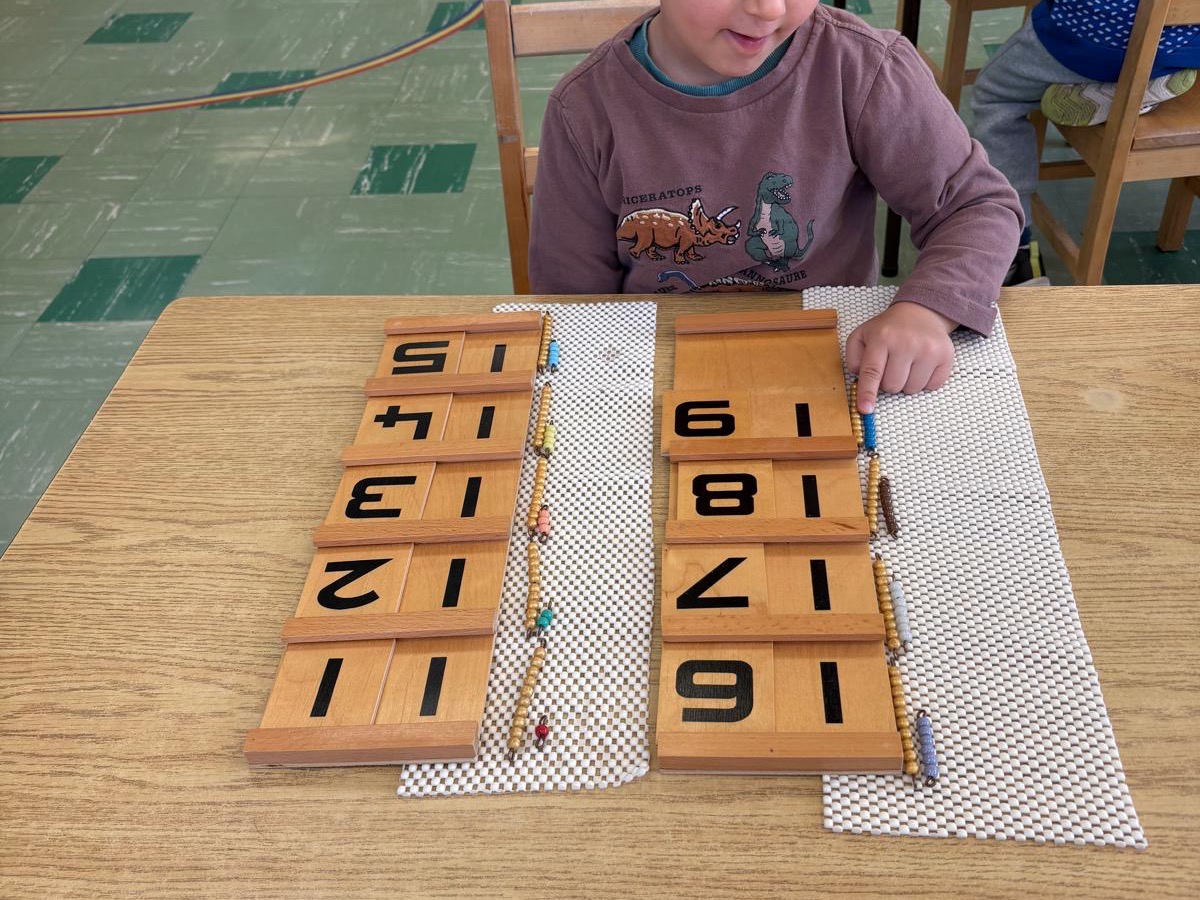 Child working with Montessori number cards and bead materials