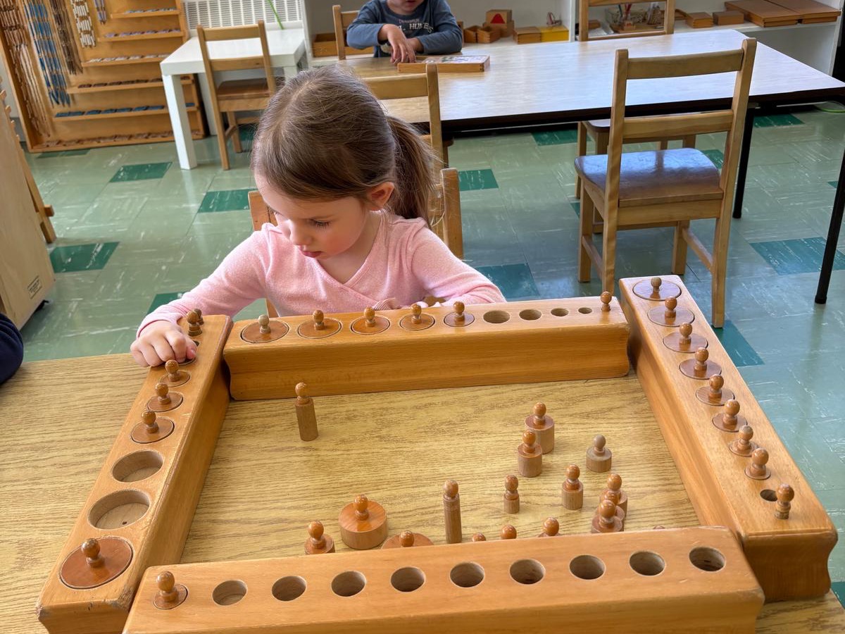 Child working with wooden Montessori materials at a classroom table